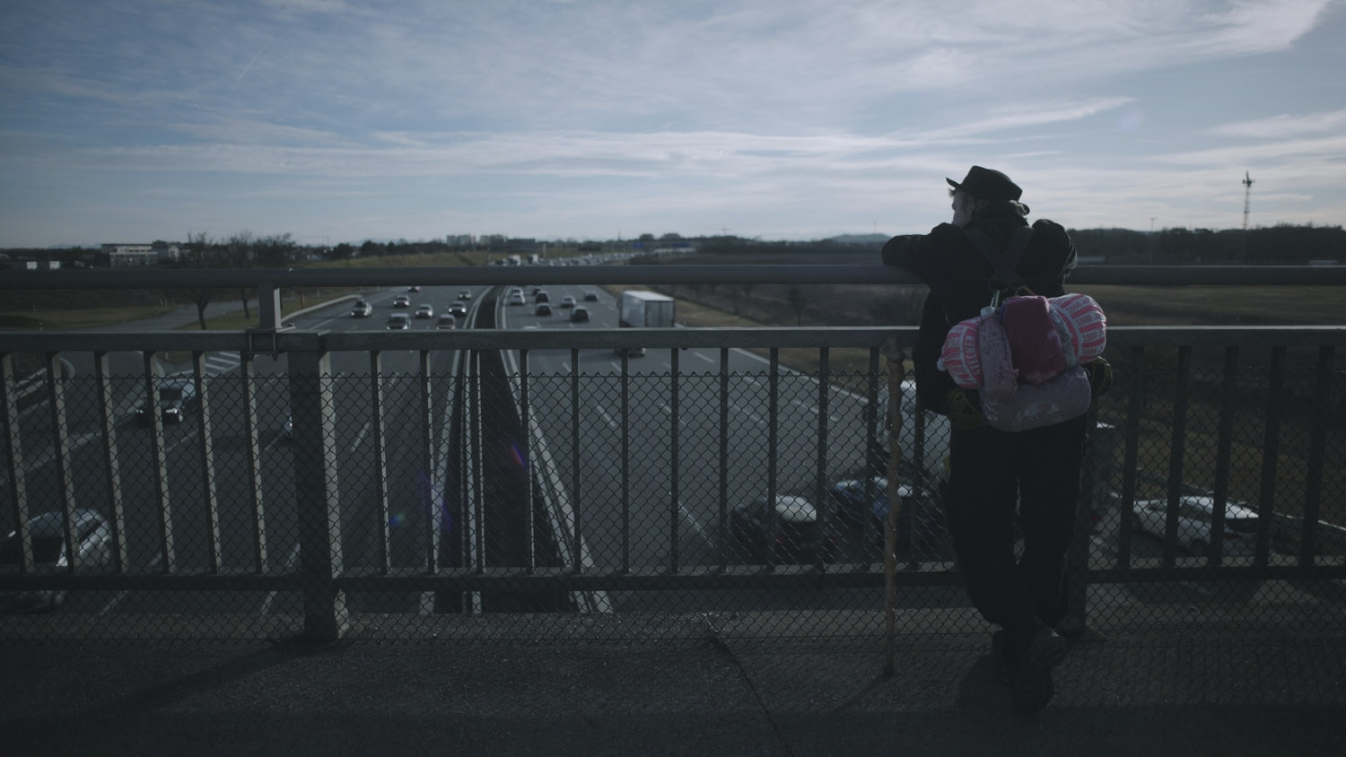 Wandergesell*in blickt auf Autobahn.